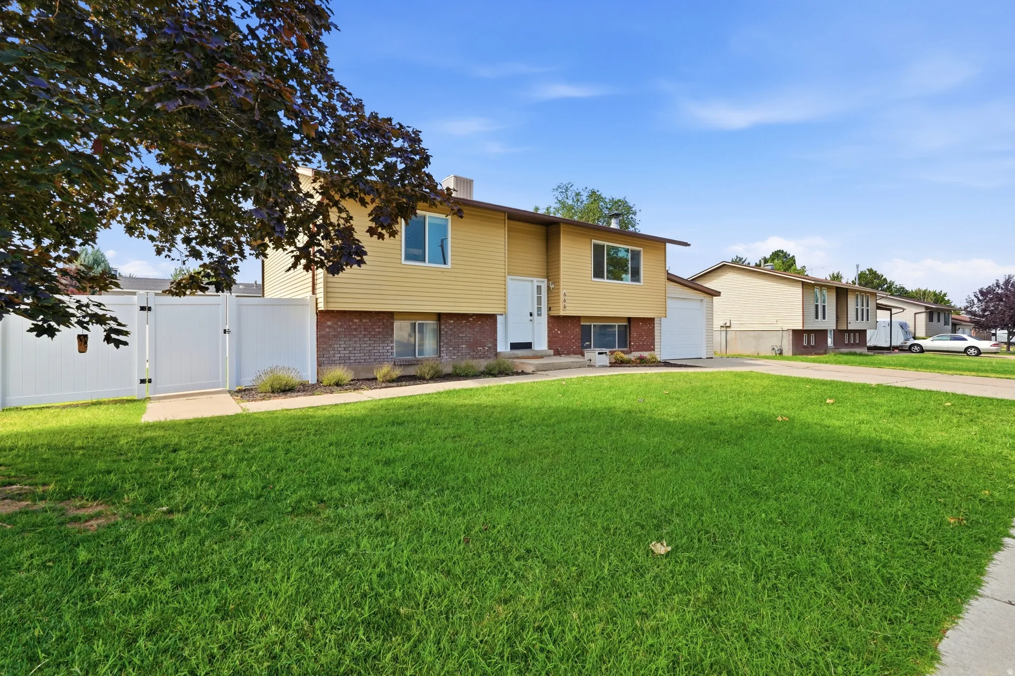 Split-level home featuring yellow siding and a brick foundation