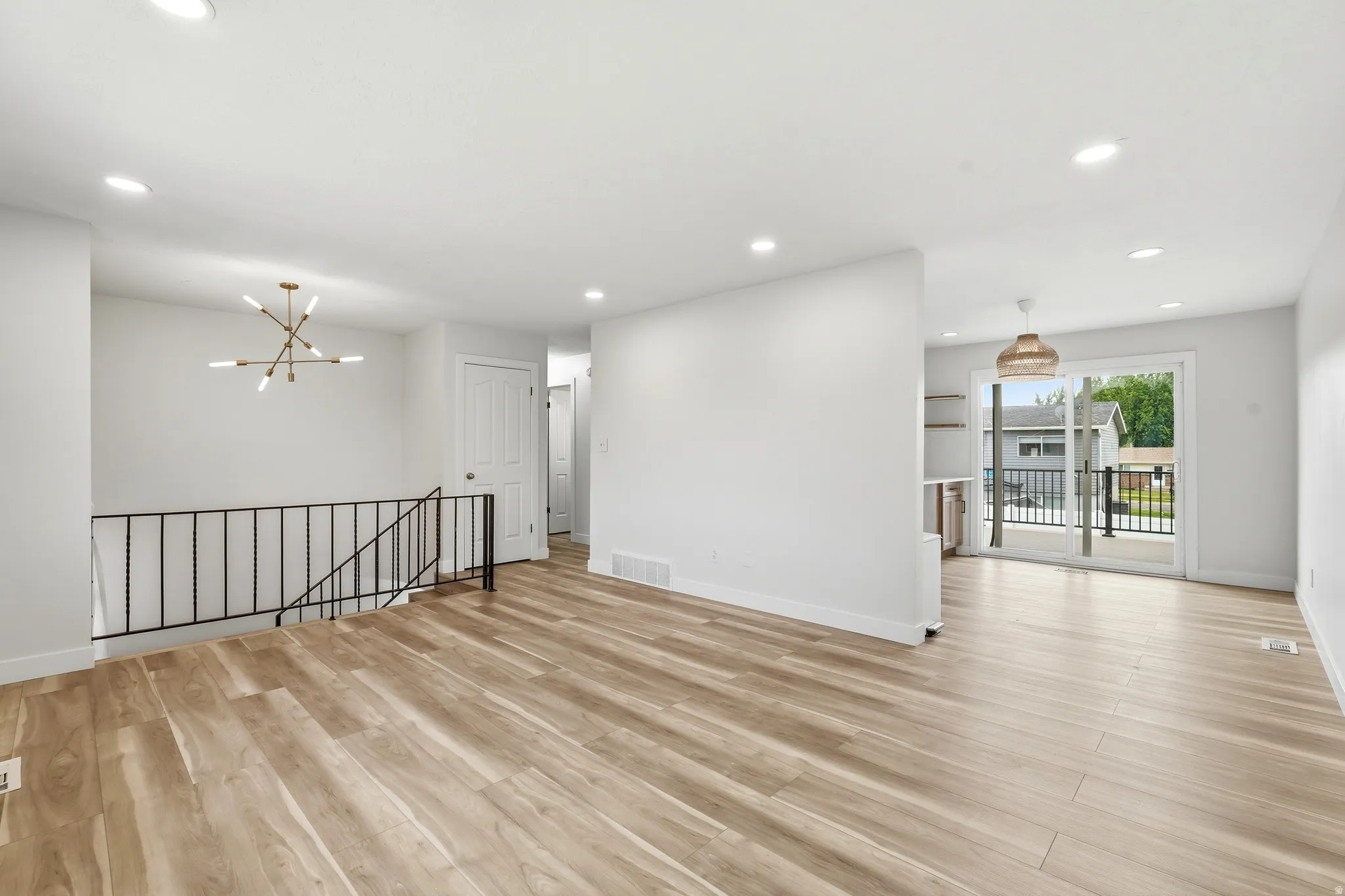 Open-concept living area with wood-finish flooring, recessed lighting, and a modern chandelier
