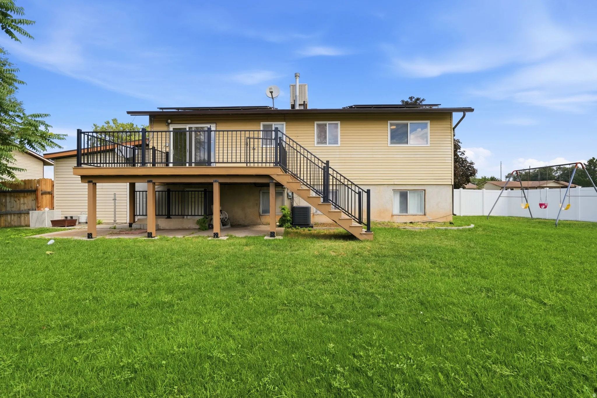Multi-level deck with black railings and a ground-level patio