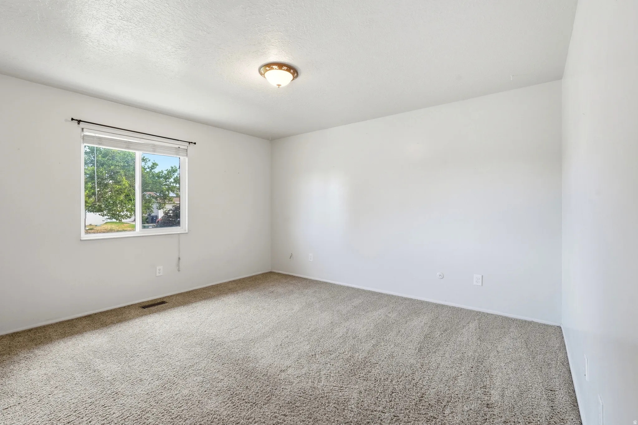 Spacious room featuring neutral carpeting and white painted walls