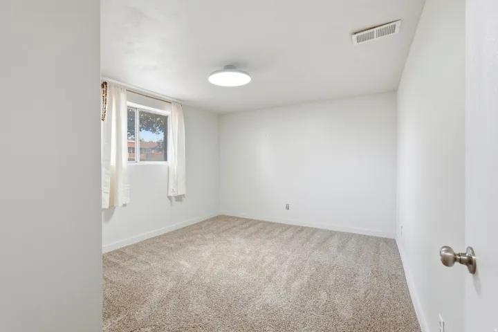 Neutral-toned carpeting extends throughout this room, complemented by white walls and a white ceiling