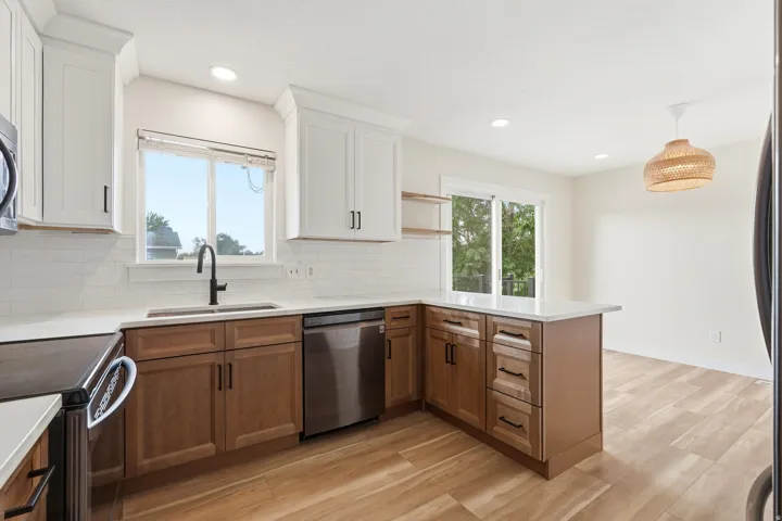 Contemporary kitchen featuring two-tone cabinetry, white countertops, a subway tile backsplash, and stainless steel appliances
