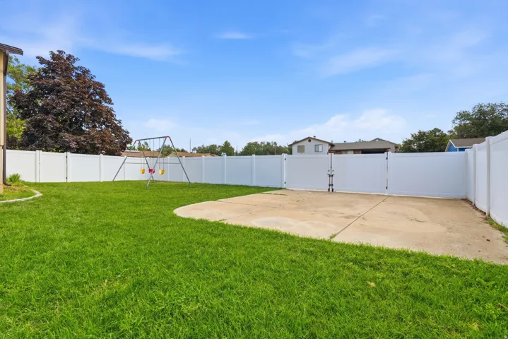 Expansive backyard featuring a lush green lawn and concrete patio