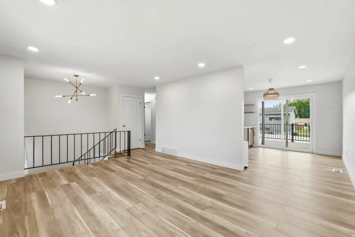 Open-concept living area with wood-finish flooring, recessed lighting, and a modern chandelier