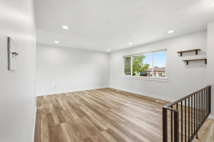 Spacious room featuring wood-finish flooring, recessed lighting, and a large window providing abundant natural light