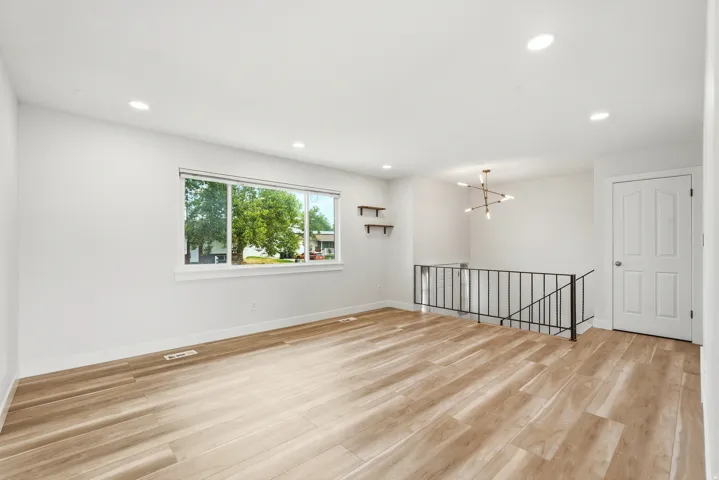 Bright room featuring wood-finish flooring, recessed lighting, and a modern chandelier