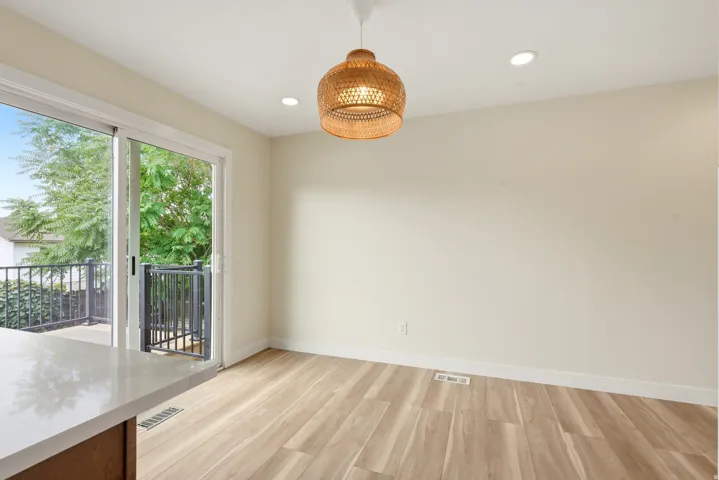 Spacious dining area featuring light wood-finish flooring, recessed lighting, and a woven pendant light fixture