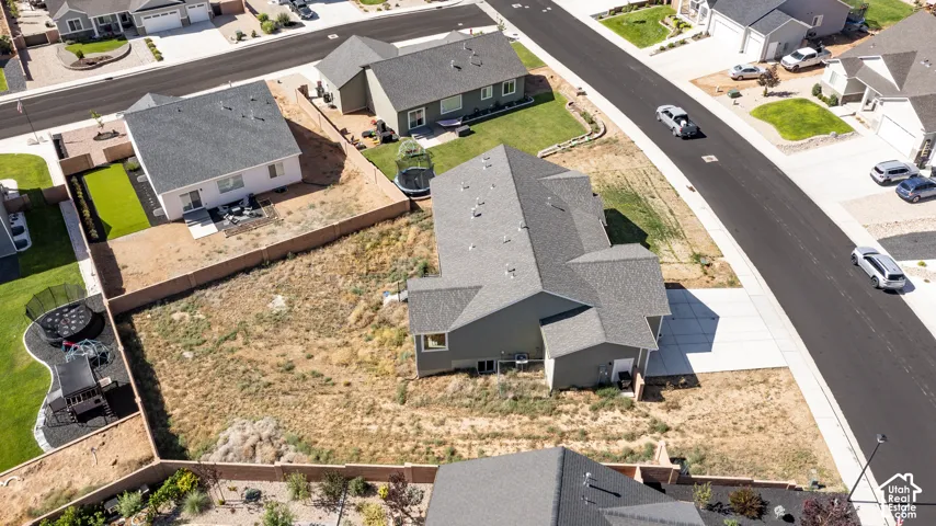 Aerial view showcasing a modern residence with a gray shingle roof and a spacious private lot