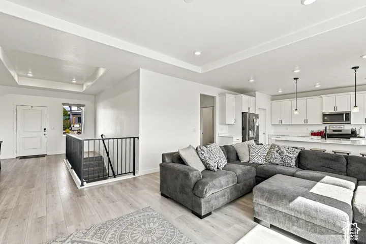 Open-concept living area featuring light wood-finish flooring, white walls, and recessed lighting