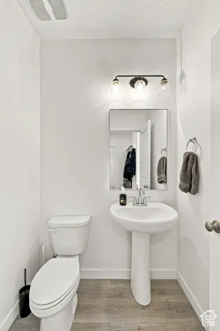 Pedestal sink with chrome faucet, framed mirror, and three-light vanity fixture