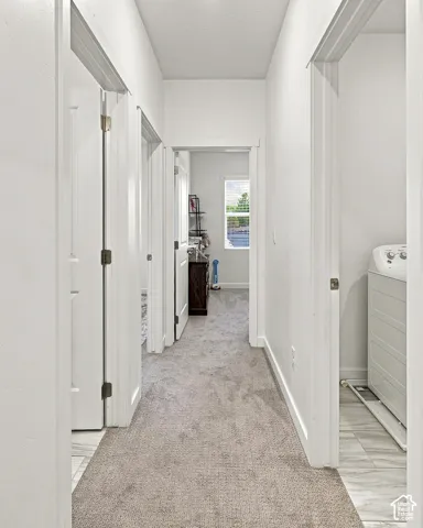 Hallway featuring light-toned carpet flooring and white walls