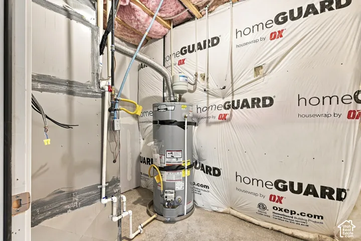 Utility space featuring a water heater, exposed piping, and electrical wiring