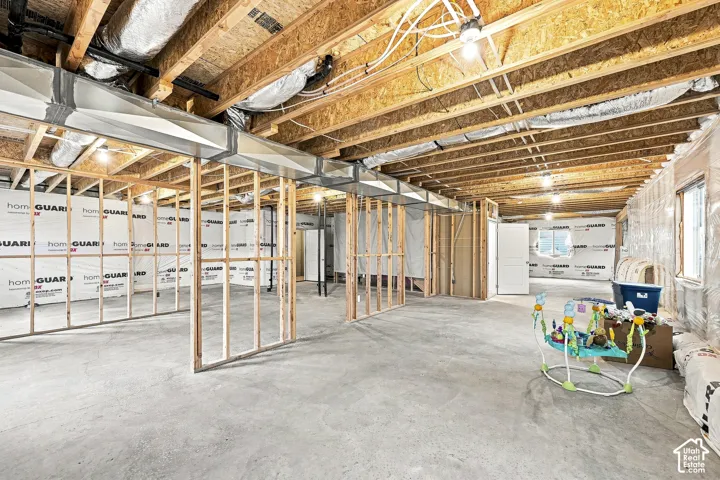 Unfinished basement featuring exposed wood joists, concrete flooring, framed interior walls, and visible HVAC ductwork