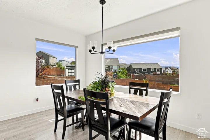 Dining area featuring expansive windows, wood-finish flooring, a modern chandelier, and white wall finishes