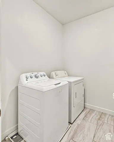 Dedicated laundry area featuring light-toned wood-finish tile flooring and crisp white walls