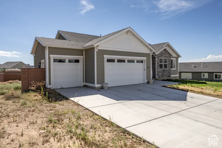 Contemporary ranch-style home featuring a two-car garage with panel windows, a single-car garage, and a concrete driveway