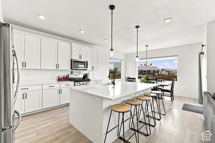 Modern kitchen featuring white cabinetry, light-toned wood-finish flooring, and a large central island with seating