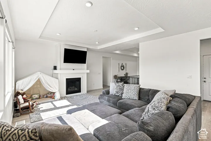 Spacious living area featuring a fireplace with white mantel, recessed lighting, and a tray ceiling