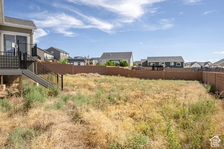 Expansive rear yard featuring a solid block perimeter wall, direct deck access, and ample space for landscaping