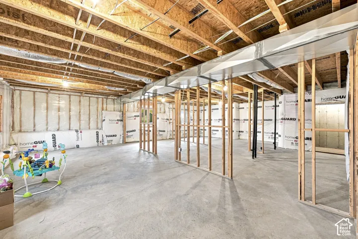 Unfinished basement featuring exposed wood joists, framed interior walls, concrete flooring, insulated exterior walls, and visible ductwork
