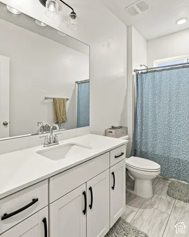 Bathroom featuring a single vanity with white cabinetry, a solid surface countertop, and an undermount sink