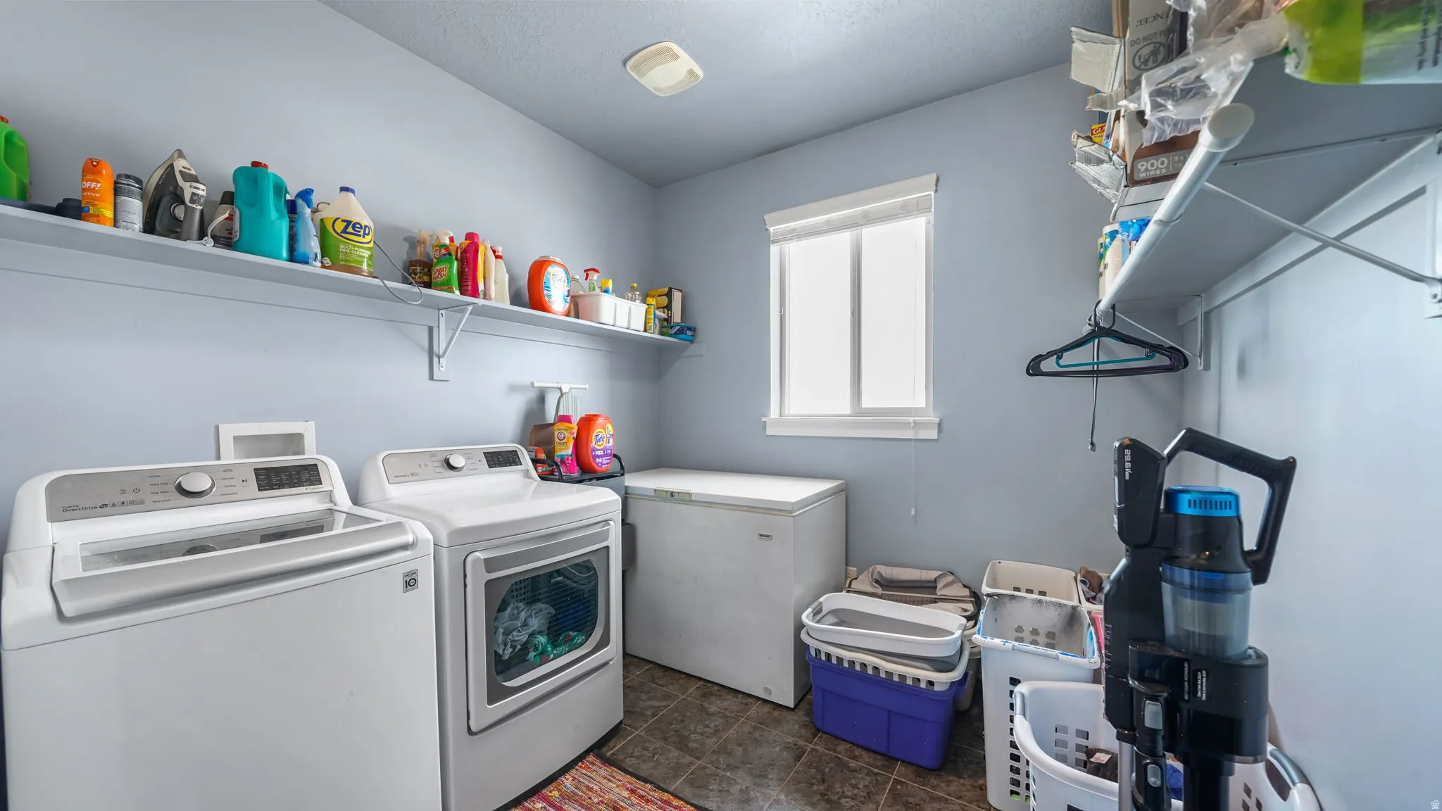 Laundry room featuring upper shelving, a single window, and tiled flooring