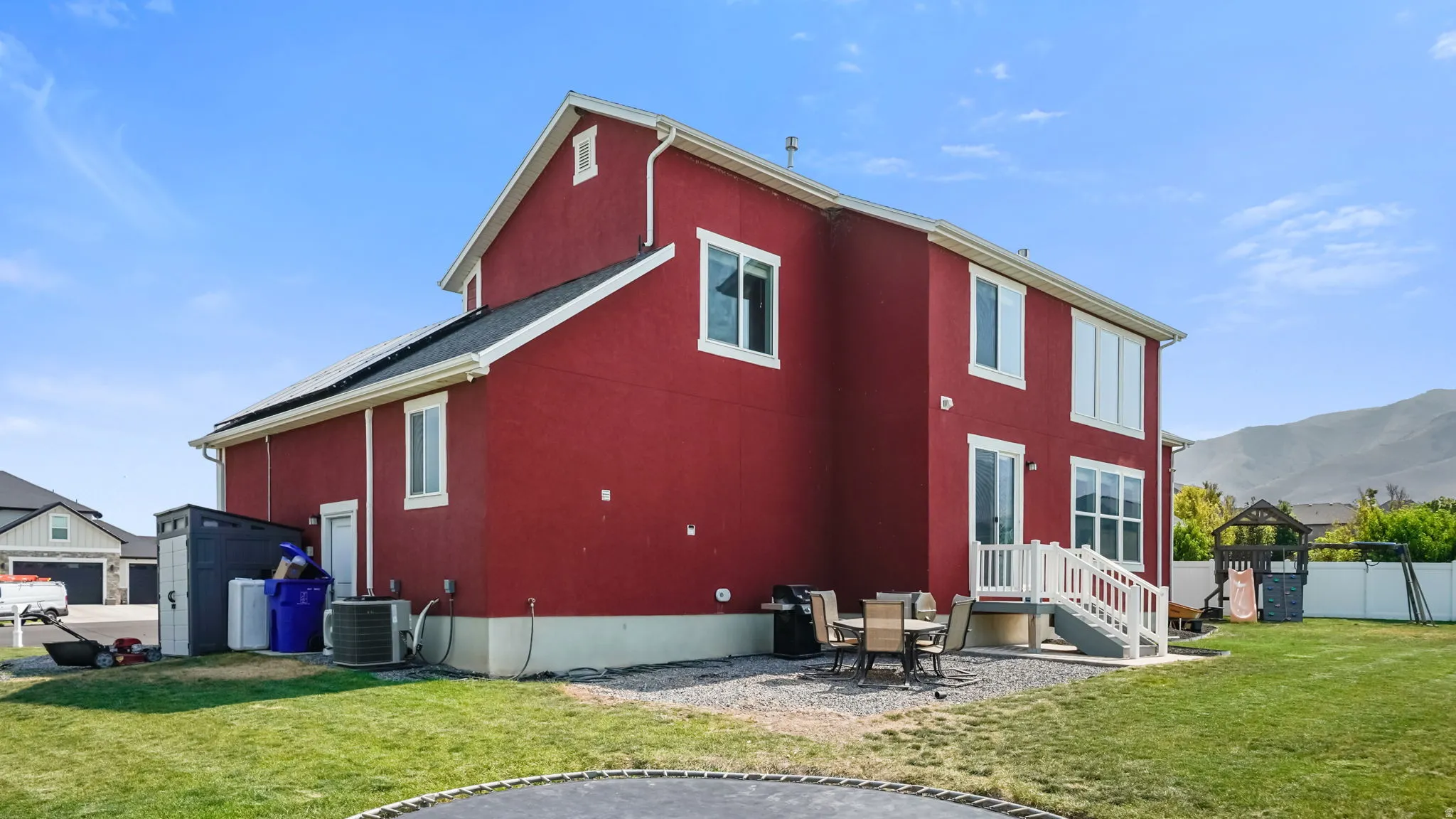 Red stucco exterior with white trim windows and a rear patio featuring a white railing