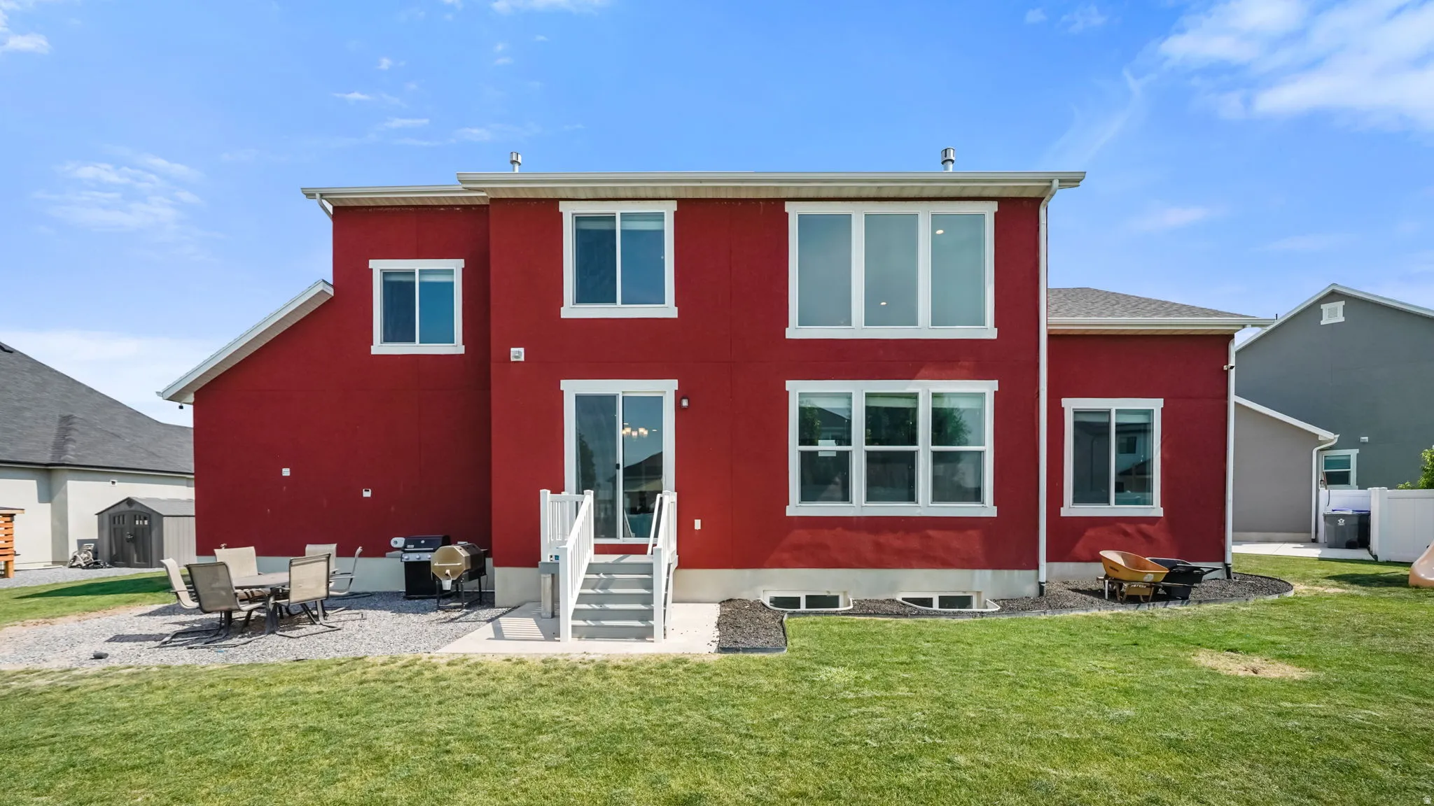 Vibrant red exterior with multiple windows, sliding glass door, and exterior stairs leading to a concrete patio