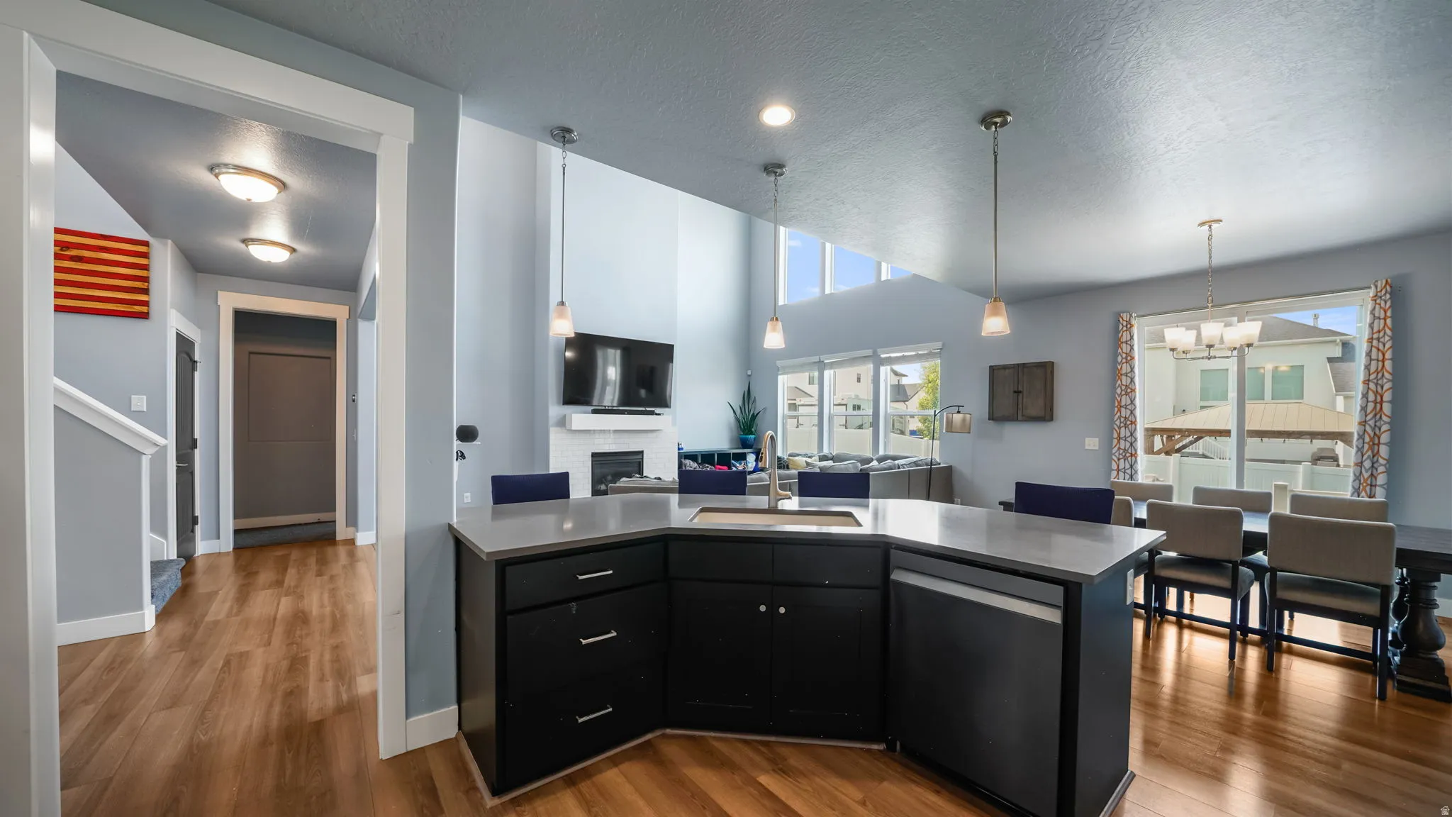 Open-concept kitchen with a large island, dark cabinetry, and light countertops