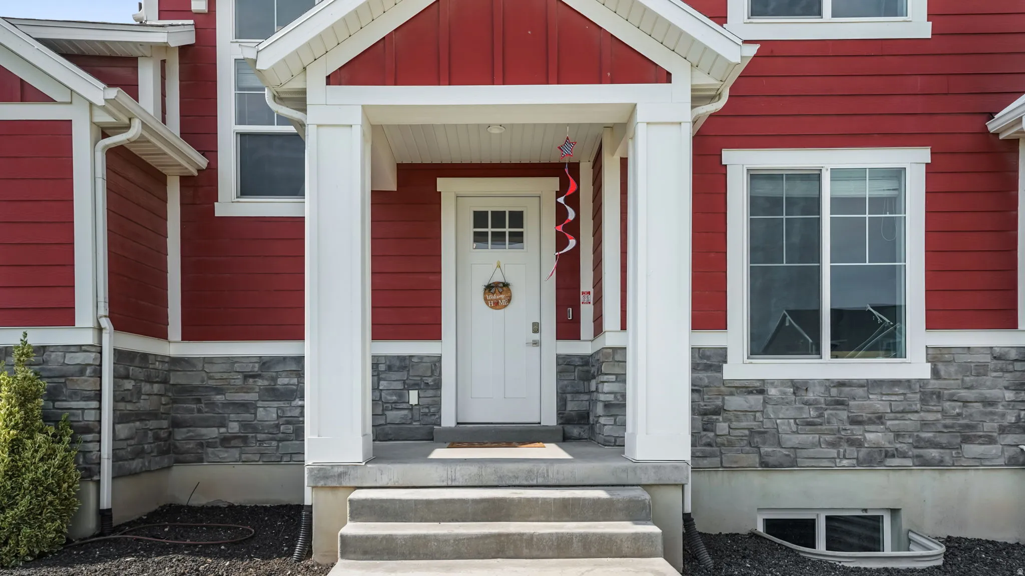 Covered front entry with white columns and red siding