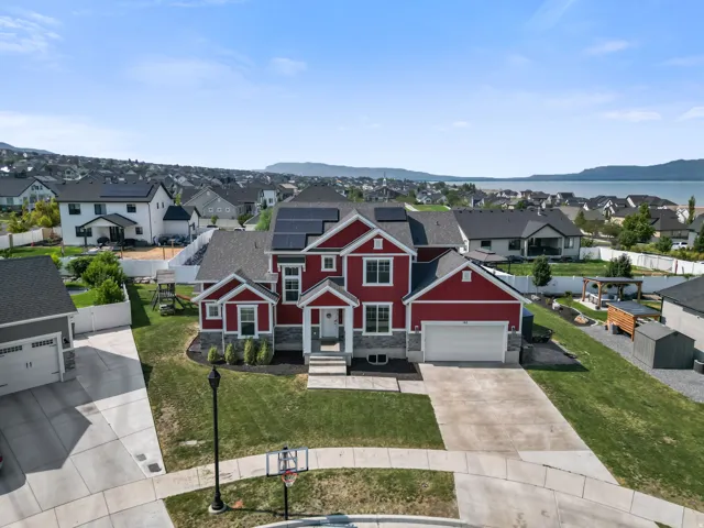 Red exterior with white trim, stone accents, two-car garage, solar panels, and a landscaped front yard