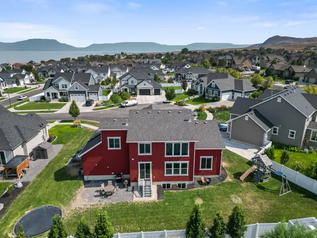 Expansive green lawn with a patio, white fencing, and mature landscaping