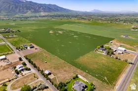 Expansive agricultural land featuring a verdant crop field and surrounding rural properties