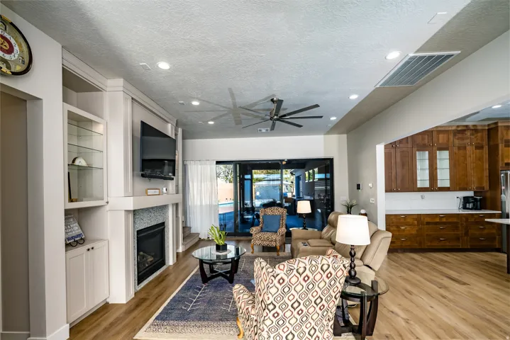 Living area featuring wood-finish flooring, a contemporary ceiling fan, and recessed lighting