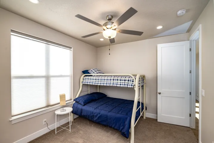 Recessed lighting and a ceiling fan fixture complement the natural light from the large window