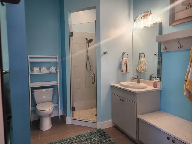 Bathroom featuring a glass-enclosed shower, a vanity with a countertop, a rectangular mirror, and a wall-mounted light fixture