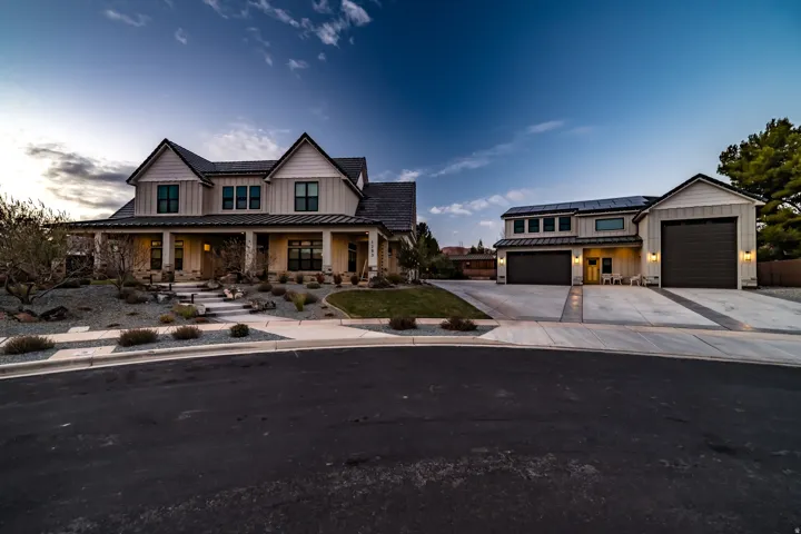 Farmhouse-style residence featuring a covered front porch, a multi-car garage, and established landscaping