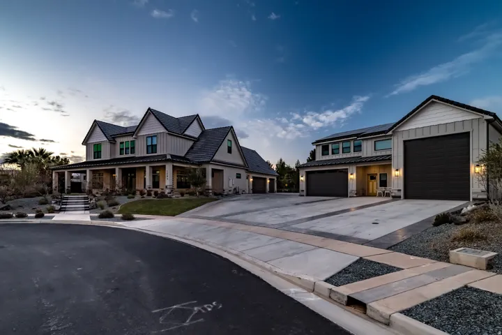 Contemporary farmhouse architecture featuring vertical siding, a covered front porch with substantial columns, and a multi-car garage