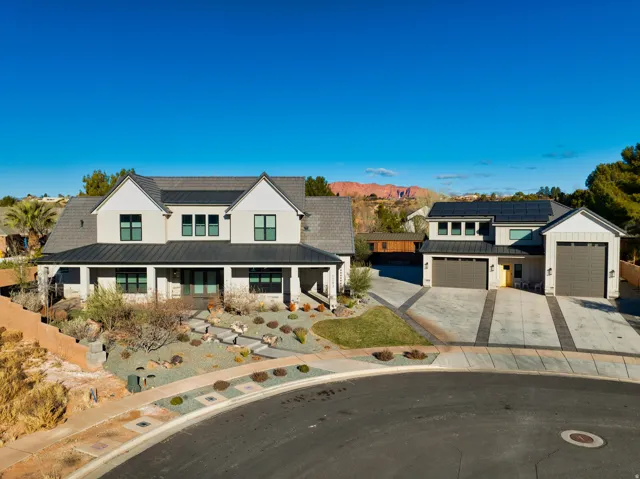 Contemporary residence with a covered porch, dark metal roof accents, and an attached two-car garage