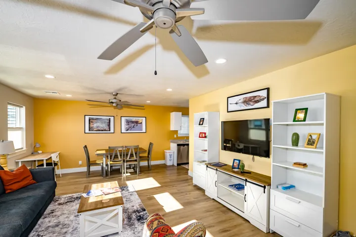 Open-concept living area with wood-finish flooring, recessed lighting, and ceiling fans