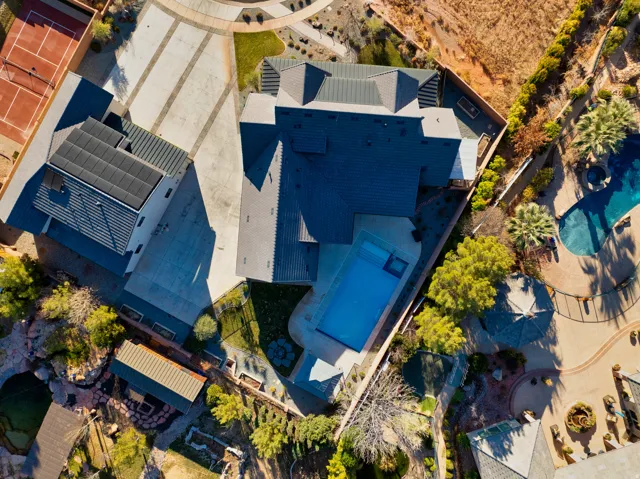 Expansive property featuring a paved motor court, two distinct swimming pools, a dedicated tennis court, and mature landscaping