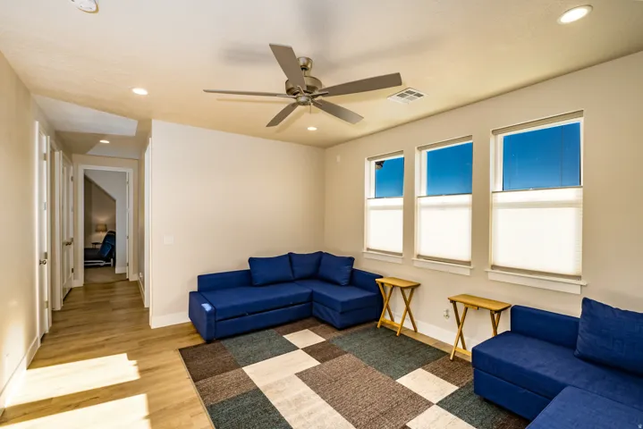 Spacious room featuring wood-finish flooring, recessed lighting, and three large windows with white blinds