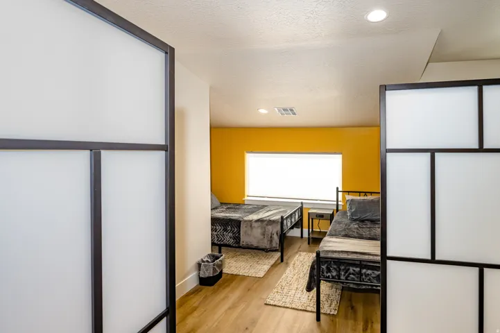 Interior space featuring wood-finish flooring, recessed lighting, a window with blinds, and white partition walls with dark framing