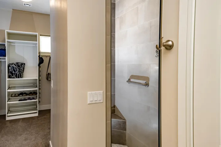 Glass-enclosed shower with light-toned tiled walls and a built-in bench