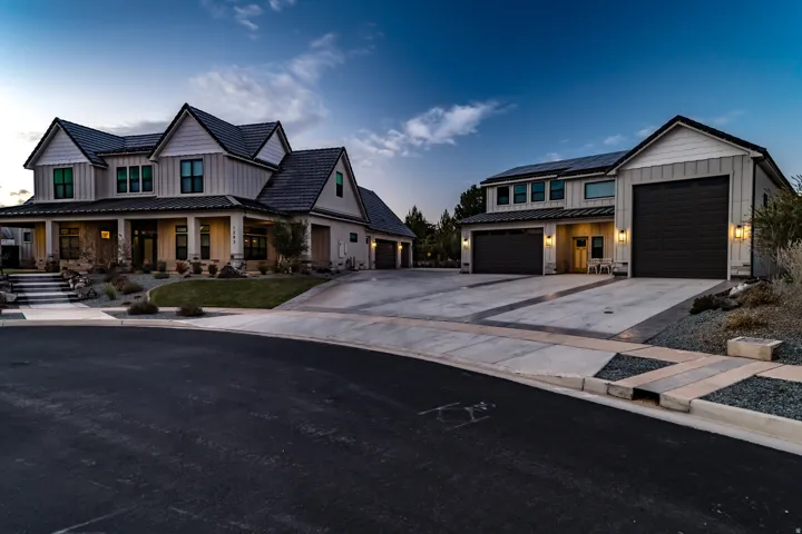Modern farmhouse style exterior featuring board and batten siding, stone accents, a deep covered front porch, multi-pane windows, and an asphalt shingle roof