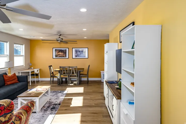 Open-concept living area featuring wood-finish flooring, recessed lighting, and multiple windows with blinds