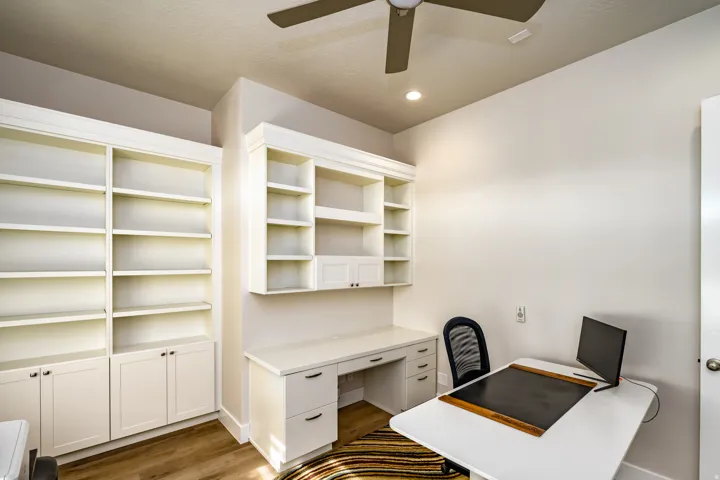 Built-in cabinetry and shelving define this room, featuring a dedicated desk area with drawers