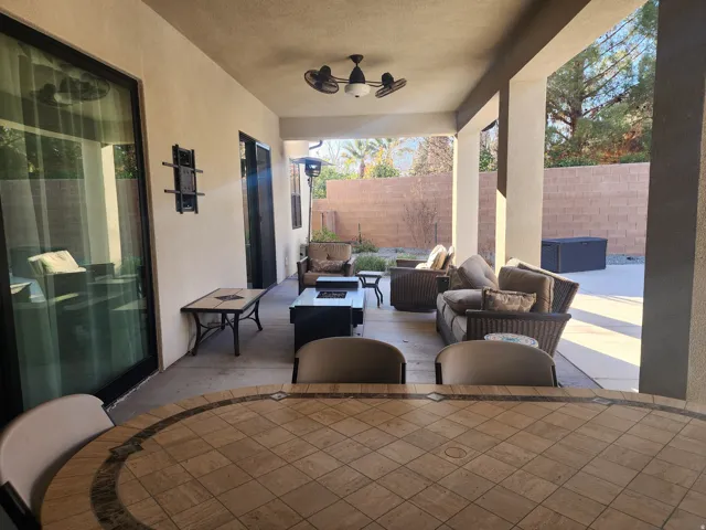 Covered patio featuring an outdoor ceiling fan, concrete flooring, and a large sliding glass door