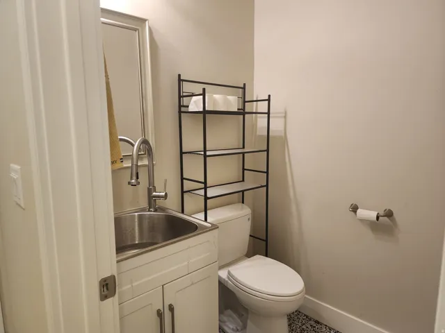 Bathroom featuring a white vanity with stainless steel sink, contemporary chrome faucet, and a wall-mounted mirror