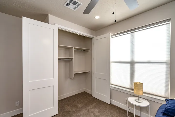 Bedroom featuring a large window with cellular blinds, a ceiling fan, recessed lighting, and a closet with custom shelving and hanging rods
